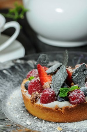 Foto de Tarta tarta con bayas, frutas y té en el fondo, de cerca - Imagen libre de derechos