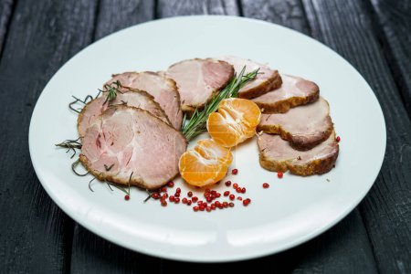 Téléchargez les photos : Jambon de porc bouilli tranché avec des herbes et de la mandarine dans une assiette - en image libre de droit