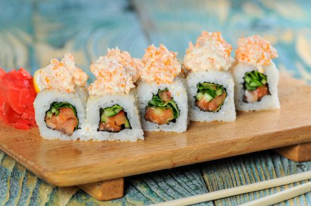 Téléchargez les photos : Rouleaux de sushi au saumon et concombre sur une planche de bois - en image libre de droit