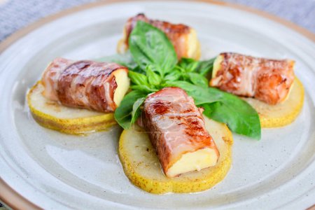Téléchargez les photos : Rouleaux géorgiens de bacon frit au fromage sur poire caramélisée close-up - en image libre de droit