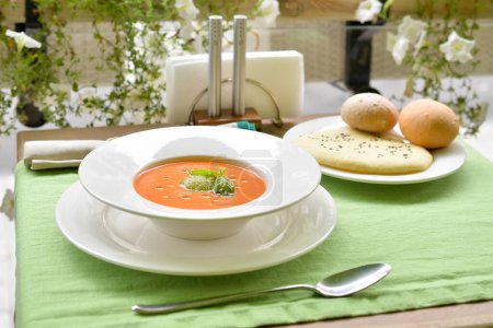 Téléchargez les photos : Soupe à la crème de tomate au basilic et pain sur la véranda aux fleurs - en image libre de droit