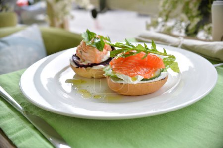 buns with salmon , salad leaves and sauce on background