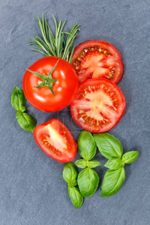 Foto de Tomatoes tomatos vegetables with basil portrait format from above on a slate top view - Imagen libre de derechos