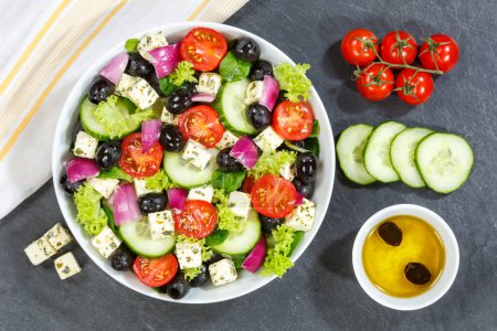 Foto de La ensalada griega con los tomates frescos las aceitunas y el queso feta la alimentación sana de arriba sobre la pizarra comen - Imagen libre de derechos