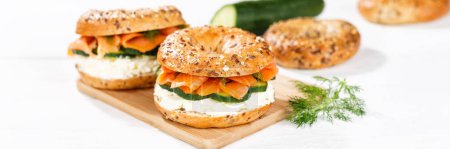 Photo for Bagel sandwich with salmon fish and cream cheese for breakfast on a kitchen board panorama - Royalty Free Image