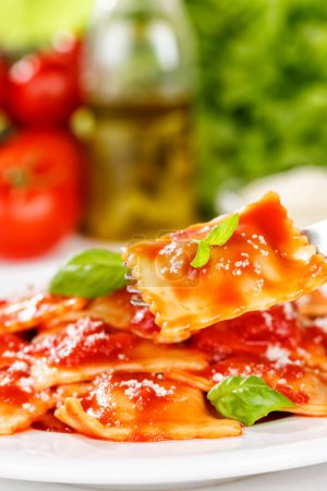 Téléchargez les photos : Farine de pâtes ravioli de l'Italie manger pour le plat du midi avec fourchette et sauce tomate sur une assiette format portrait - en image libre de droit