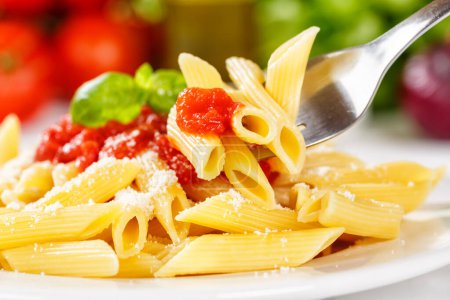 Photo for Penne Rigatoni Rigate eating pasta eat on fork meal from Italy lunch with tomato sauce on a plate - Royalty Free Image