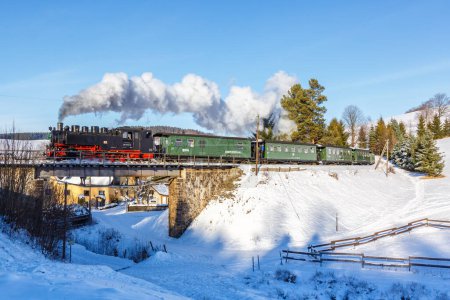 Foto de Sehmatal, Alemania - 18 de diciembre de 2022 Fichtelbergbahn tren de vapor locomotora ferroviaria en un puente en invierno en Sehmatal, Alemania. - Imagen libre de derechos