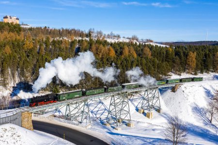 Photo for Oberwiesenthal, Germany - December 18, 2022 Fichtelbergbahn steam train locomotive railway on a bridge in winter aerial view in Oberwiesenthal, Germany. - Royalty Free Image