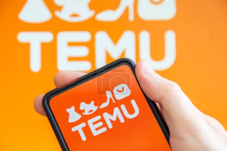 Téléchargez les photos : Stuttgart, Allemagne - 19 juillet 2023 : Main tenant un téléphone portable avec logo Temu marché en ligne ecommerce écran d'ordinateur à Stuttgart, Allemagne. - en image libre de droit