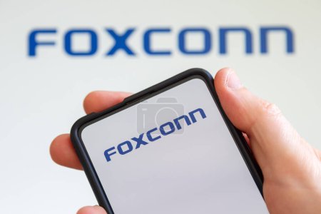 Téléchargez les photos : Stuttgart, Allemagne - 20 juillet 2023 : Main tenant un téléphone portable avec le logo Foxconn de l'écran du producteur d'ordinateurs à Stuttgart, Allemagne. - en image libre de droit