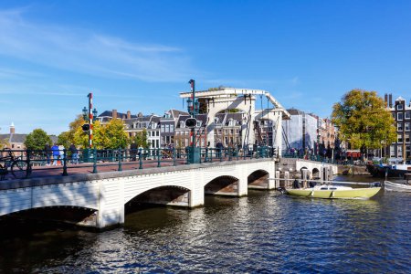 Foto de Puente Magere Brug sobre el canal de Amstel y casas holandesas tradicionales que viajan en Amsterdam, Países Bajos - Imagen libre de derechos