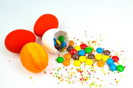 Téléchargez les photos : Joyeux Pâques. Œuf de Pâques cassé avec des décorations de bonbons multicolores. sur fond blanc. Œufs colorés - en image libre de droit