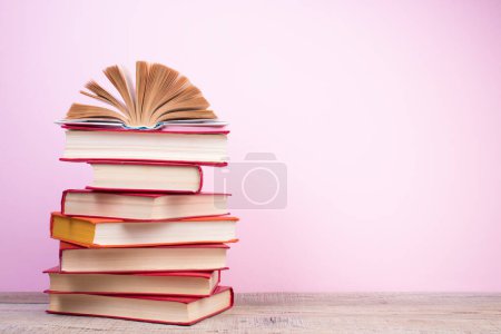 Photo for Composition with hardback books, fanned pages on wooden deck table and pink background. Books stacking. Back to school. Copy Space. Education background. Tuition payment. - Royalty Free Image