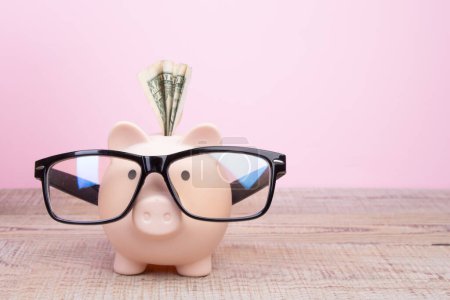 Photo for Piggy bank wearing a black glasses over pink background - Royalty Free Image