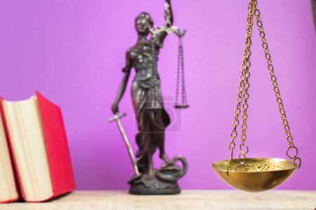 Photo for Law concept - Open law book, Judge's gavel, scales, Themis statue on table in a courtroom or law enforcement office. Wooden table, purple background. - Royalty Free Image