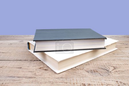 Photo for Open book. Composition with hardback books, fanned pages on wooden deck table and purple background. Books stacking. Back to school. Copy Space. Education background - Royalty Free Image