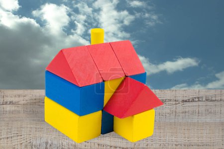 Téléchargez les photos : Maison faite de blocs de constructeur d'enfants sur une table en bois contre le ciel - en image libre de droit