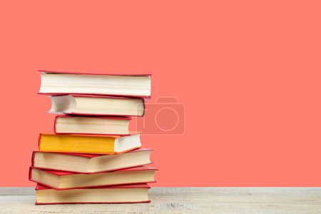 Téléchargez les photos : Composition avec des livres à dos rigide sur table de pont en bois et fond orange. Des livres empilés. Je retourne à l'école. Espace de copie. Formation initiale - en image libre de droit