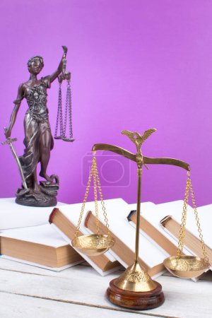 Photo for Law concept - Open law book, Judge's gavel, scales, Themis statue on table in a courtroom or law enforcement office. Wooden table, purple background - Royalty Free Image