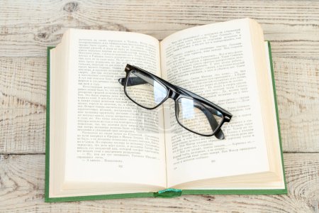 Photo for Open book, hardback books, glasses on wooden table. Back to school. Education. Copy space for text - Royalty Free Image