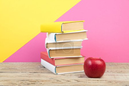 Photo for Books stacking. Books on wooden table and pink, yellow background. Back to school. Copy space for ad text - Royalty Free Image