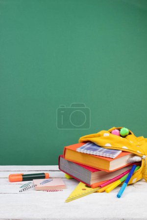 Téléchargez les photos : Sac à dos avec différentes papeterie colorée sur la table. Fond vert. Retour à l'école - en image libre de droit