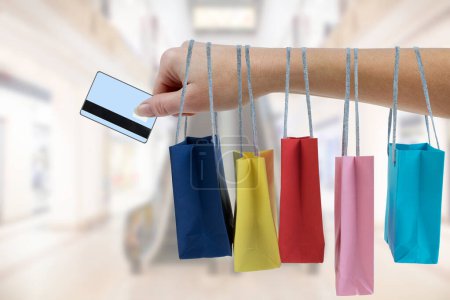 Téléchargez les photos : Crop main féminine tenant des sacs en papier coloré sur le fond du centre commercial - en image libre de droit