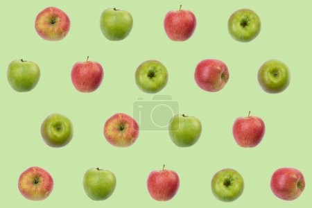 Téléchargez les photos : Modèle de fruits colorés de pommes rouges fraîches et vertes sur fond vert. conception de texture pour les textiles, papier peint, tissu. De vue du dessus - en image libre de droit