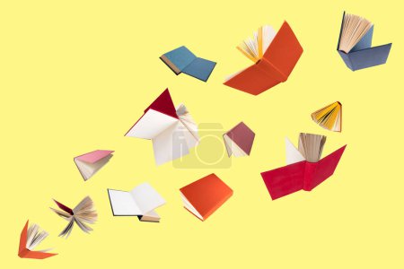 Photo for Colorful hardcover books flying isolated on yellow background - Royalty Free Image
