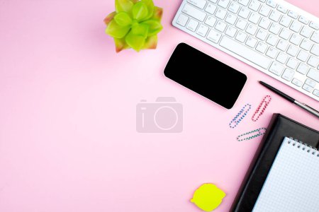 Téléchargez les photos : Table de bureau rose avec ordinateur, stylo et une tasse de café, beaucoup de choses. Vue supérieure avec espace de copie - en image libre de droit