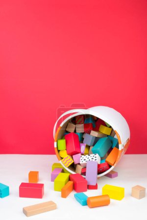 Foto de Juguete para niños, constructor de madera, vertido de un cubo sobre un fondo rojo - Imagen libre de derechos
