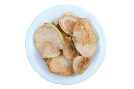 Téléchargez les photos : Trancher les pommes séchées dans une assiette isolée sur fond blanc. Pomme biologique maison - en image libre de droit