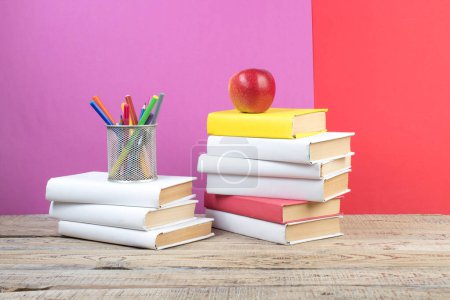 Photo for Books stacking. Books on wooden table and red, purple background. Back to school. Copy space for ad text - Royalty Free Image
