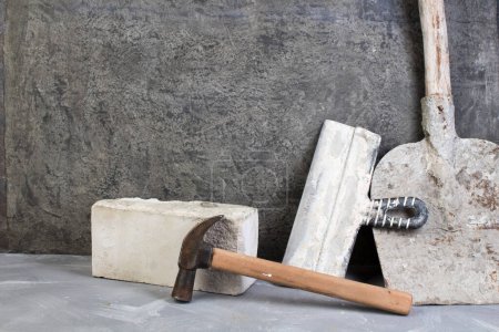 Photo for Bricks, hammer, putty knife, old, dirty shovel on the gray concrete background. Copy space. Top view - Royalty Free Image