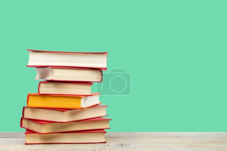 Photo for Composition with hardback books on wooden deck table and green background. Books stacking. Back to school. Copy Space. Education background - Royalty Free Image