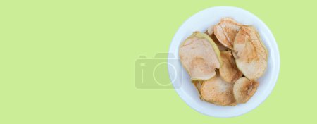 Photo for Sliced, dried apples in a plate isolated on green background. Homemade organic apple - Royalty Free Image