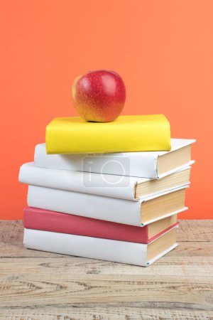Photo for Books stacking. Books on wooden table and orange background. Back to school. Copy space for ad text - Royalty Free Image