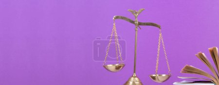 Photo for Law concept - Open law book, Judge's gavel, scales, Themis statue on table in a courtroom or law enforcement office. Wooden table, purple background, Banner - Royalty Free Image