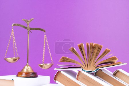 Photo for Law concept - Open law book, Judge's gavel, scales, Themis statue on table in a courtroom or law enforcement office. Wooden table, purple background - Royalty Free Image