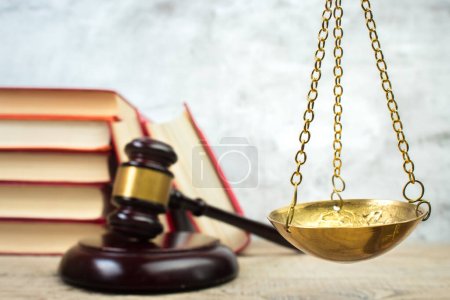 Photo for Law concept - Open law book, Judge's gavel, scales, Themis statue on table in a courtroom or law enforcement office. Wooden table, gray concrete background. - Royalty Free Image