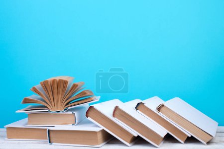 Photo for Open books, hardback colorful books on wooden table. blue background. Back to school. Copy space for text. Education business concept - Royalty Free Image