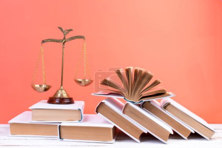 Photo for Law concept - Open law book, Judge's gavel, scales, Themis statue on table in a courtroom or law enforcement office. Wooden table, orange background - Royalty Free Image