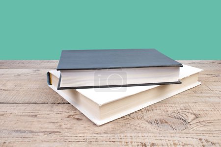 Photo for Composition with hardback books, fanned pages on wooden deck table and green background. Books stacking. Back to school. Copy Space. Education background. Tuition payment. - Royalty Free Image