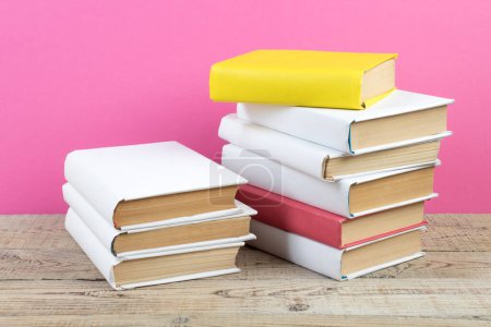 Foto de Libros apilados. Libros sobre mesa de madera y fondo rosa. De vuelta a la escuela. Copiar espacio para texto del anuncio - Imagen libre de derechos