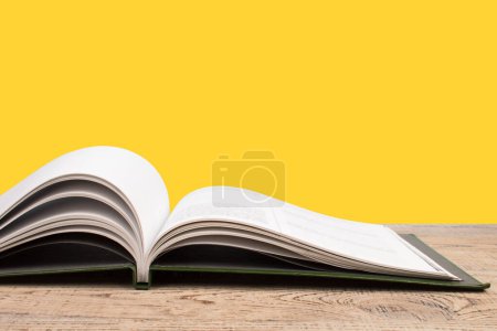 Photo for Open book. Composition with hardback books, fanned pages on wooden deck table and yellow background. Books stacking. Back to school. Copy Space. Education background. Tuition payment. - Royalty Free Image
