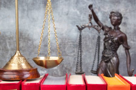 Photo for Law concept - Open law book, Judge's gavel, scales, Themis statue on table in a courtroom or law enforcement office. Wooden table, gray concrete background. - Royalty Free Image