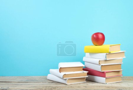 Téléchargez les photos : Des livres empilés. Livres sur table en bois et fond bleu. Je retourne à l'école. Espace de copie pour texte publicitaire - en image libre de droit