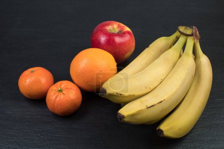 Téléchargez les photos : Des fruits. Bananes, pommes, oranges mandarines sur fond noir - en image libre de droit