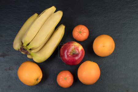 Téléchargez les photos : Des fruits. Bananes, pommes, oranges mandarines sur fond noir - en image libre de droit